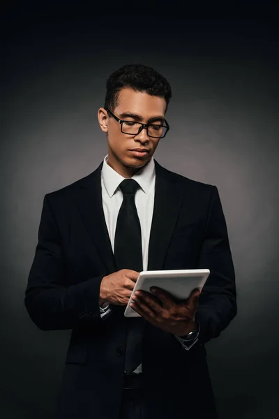 暗い背景にデジタルタブレットを使用して眼鏡でアフリカ系アメリカ人のビジネスマン — ストック写真