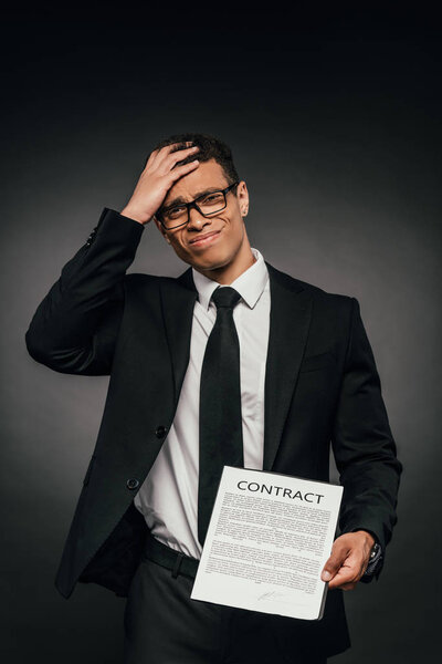 failed african american businessman showing contract on dark background