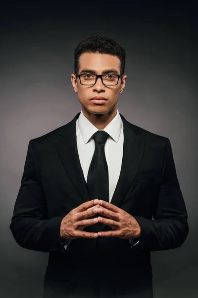 successful african american businessman in suit and glasses on dark background