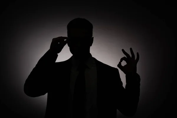 バックライトでOkサインを見せるビジネスマンの黒いシルエット — ストック写真
