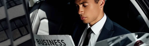 車の中でビジネス新聞を読むアフリカ系アメリカ人ビジネスマンのパノラマショット — ストック写真