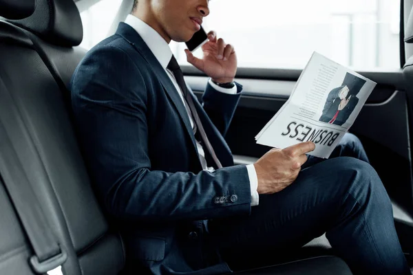 アフリカ系アメリカ人ビジネスマンがビジネス新聞を読み 車の中でスマートフォンで話す部分 — ストック写真