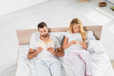 evde kitap ile yatakta yatan güzel çift yüksek açı görünümü 