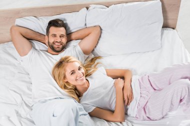 evde yatakta rahatlatıcı pijama gülümseyen çift üst görünümü