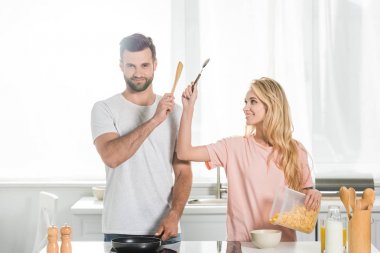 mutfakta birlikte kahvaltı pişirirken güzel çift tutarak spatula ve kaşık