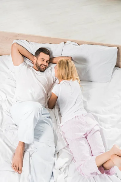 在睡衣的夫妇在家里放松在床上的顶视图 — 图库照片