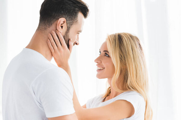 beautiful romantic couple embracing at home near window