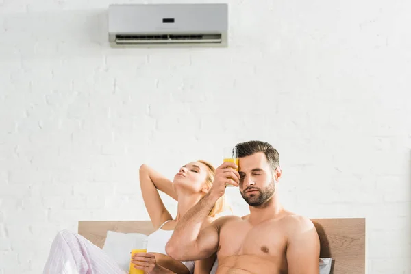 Casal Com Suco Laranja Sofrendo Calor Sob Condicionado Cama Casa — Fotografia de Stock