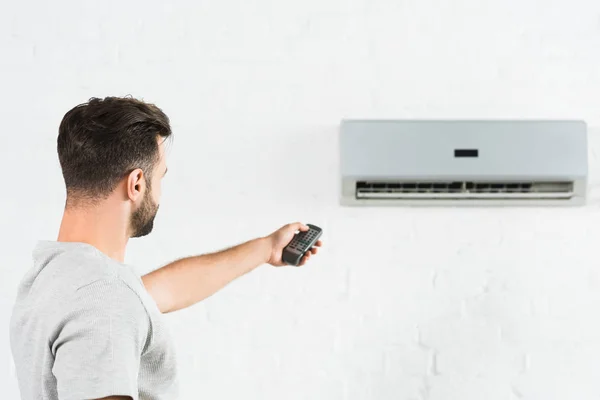 自宅のエアコンの熱と切り替え温度に苦しむ男性の側面図 — ストック写真