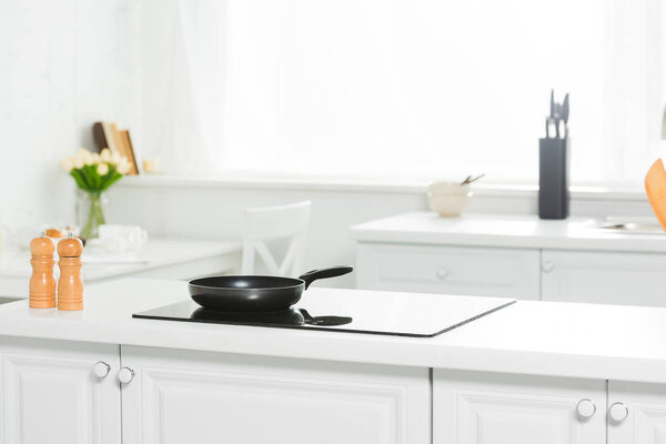 modern kitchen with white counter, cooker and frying pan