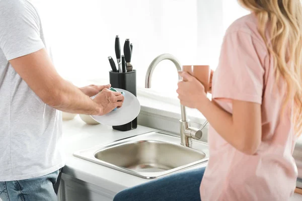 男人在厨房洗碗 而女人拿着咖啡杯 — 图库照片