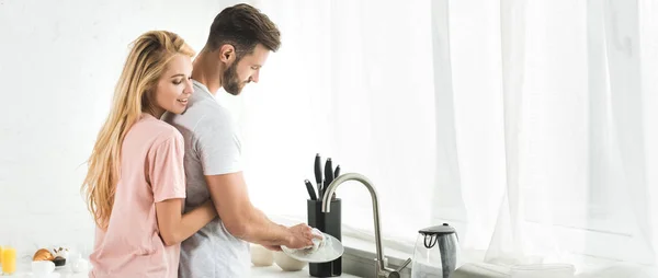 Панорамный Снимок Женщины Обнимающей Мужчину Моющего Посуду Кухне — стоковое фото