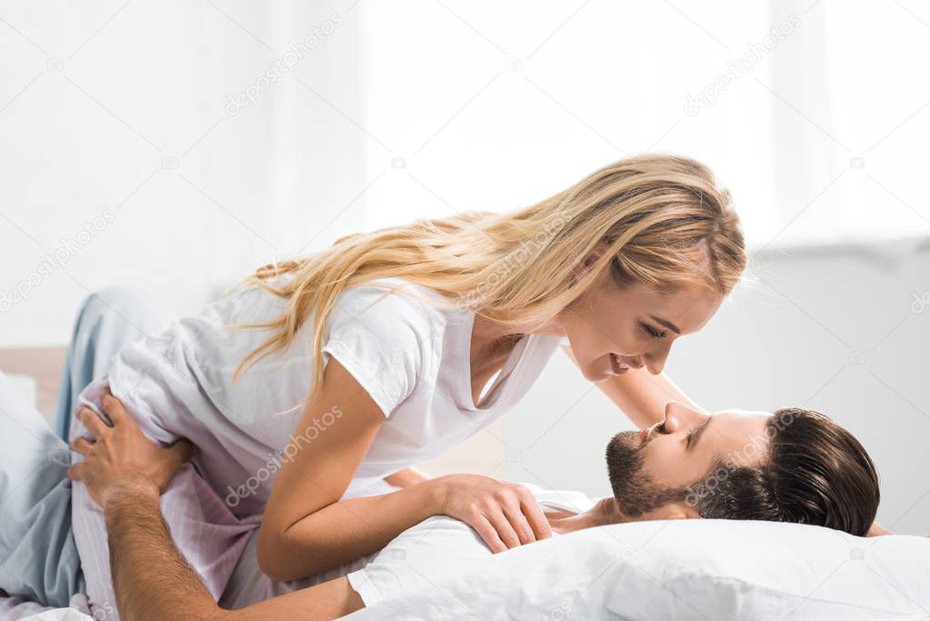 beautiful couple lying in bed and embracing at home