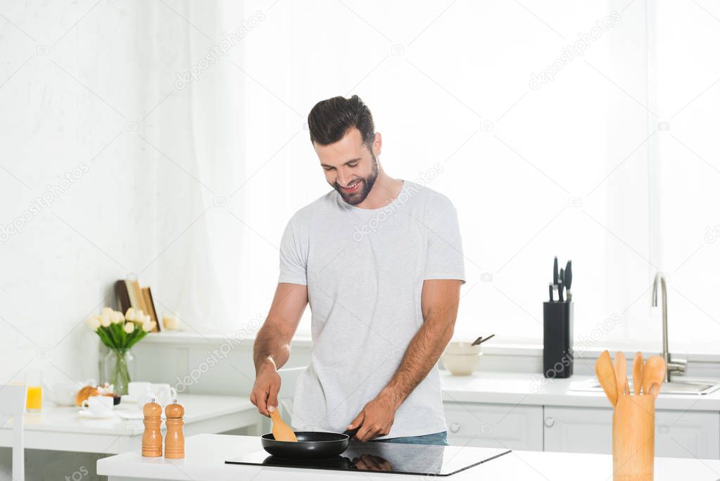 Man cooking with spatula and frying pan at kitchen in morning