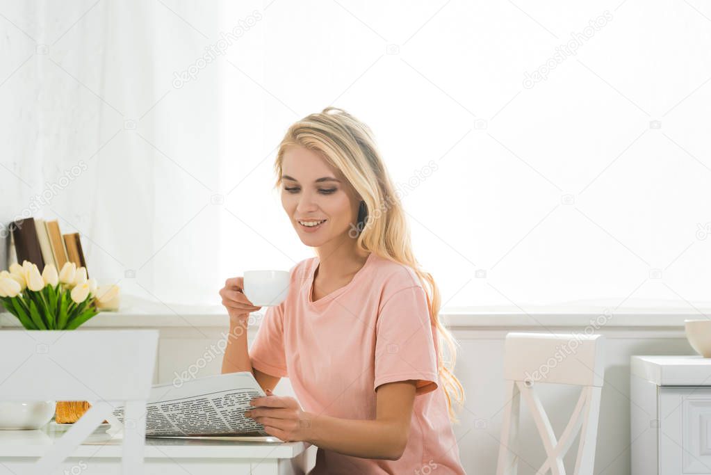 beautiful woman with coffee cup and newspaper at kitchen table in morning