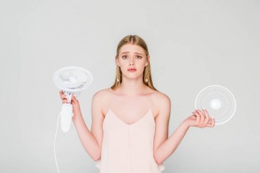 gri izole Elektrik Fan tutan güzel şaşkın genç kadın