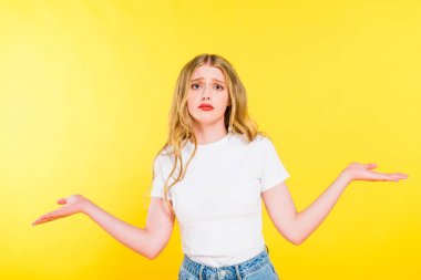 beautiful sad blonde young woman doing shrug gesture Isolated On yellow clipart