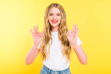 beautiful smiling blonde young woman showing ok signs On yellow clipart