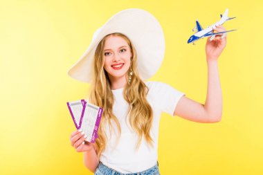 beautiful girl with plane model and air tickets On yellow clipart