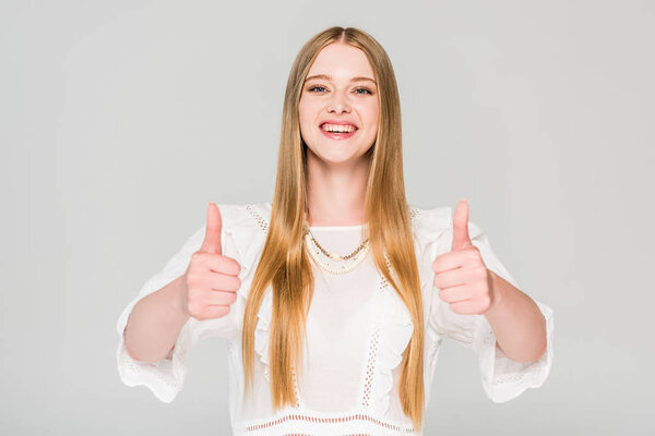 beautiful smiling girl showing thumbs up isolated on grey