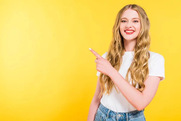 Lachende Blonde Jonge Vrouw Wijzend Met Vinger Geïsoleerd Geel — Stockfoto