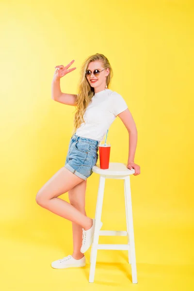 Beautiful Girl Sunglasses Chair Soda Drink Showing Peace Sign Yellow — Stock Photo, Image