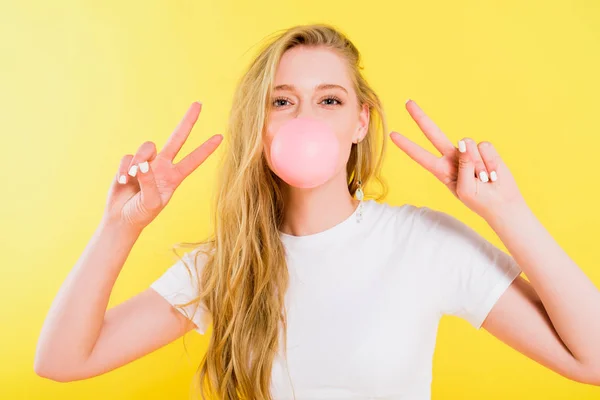 Piękna Dziewczyna Dmuchanie Bubble Gum Robienie Znaków Pokojowych Izolowane Żółto — Zdjęcie stockowe
