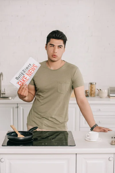 Miło Asian Mężczyzna Patrząc Daleko Trzymając Fałszywe Gazety News Kuchni — Zdjęcie stockowe