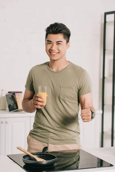 Sorrindo Asiático Homem Segurando Vidro Suco Laranja Mostrando Polegar Para — Fotografia de Stock