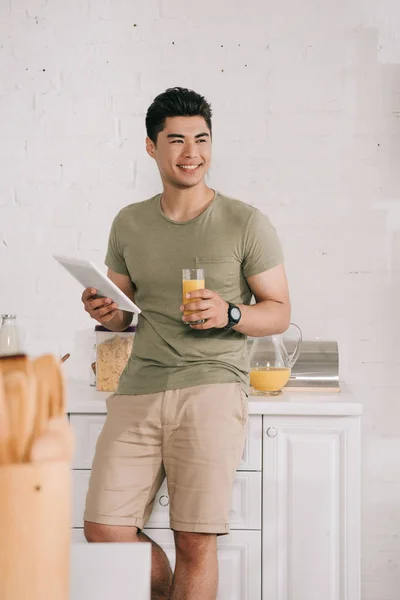 Handsome Asian Man Holding Glass Orange Juice Digital Tablet While — Stock Photo, Image