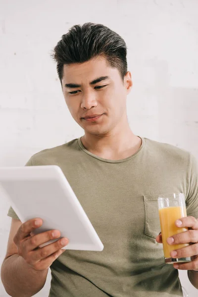 オレンジジュースのグラスを持ちながら偽の新聞を読むハンサムなアジアの男 — ストック写真