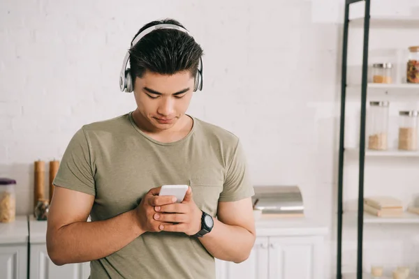 Mladý Asijský Muž Používající Smartphone Při Poslechu Hudby Sluchátkách — Stock fotografie