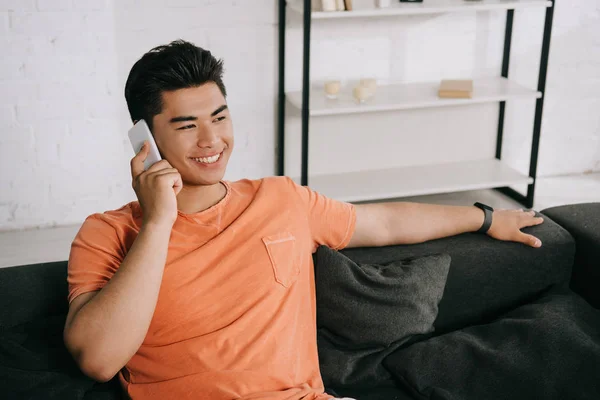 Handsome Asian Man Talking Smartphone While Sitting Sofa Looking Away — Stock Photo, Image