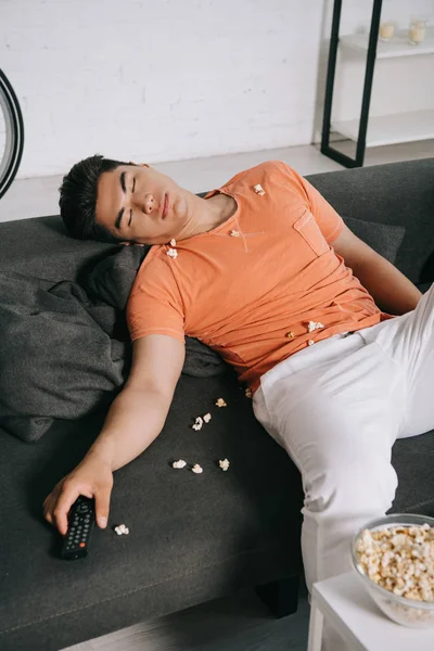 Esausto Asiatico Uomo Dormire Divano Vicino Tavolo Con Ciotola Popcorn — Foto Stock