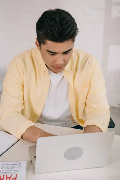 Uppmärksam Asiatisk Man Sitter Vid Skrivbordet Och Använder Laptop Hemma — Stockfoto