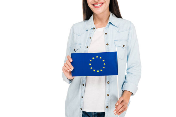 cropped view of smiling girl in denim jacket holding flag of Europe isolated on white