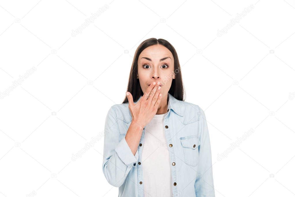 excited brunette woman covering mouth with hand isolated on white
