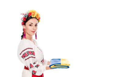 side view of brunette young woman in national Ukrainian costume holding flag isolated on white clipart