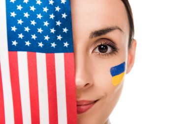 yüzünde beyaz izole Amerikan bayrağı tutan boyalı Ukrayna bayrağı ile gülümseyen genç kadın
