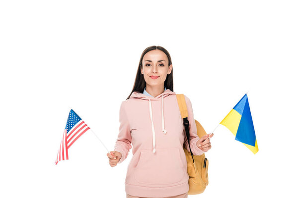 smiling student with backpack holding Ukrainian and American flags isolated on white