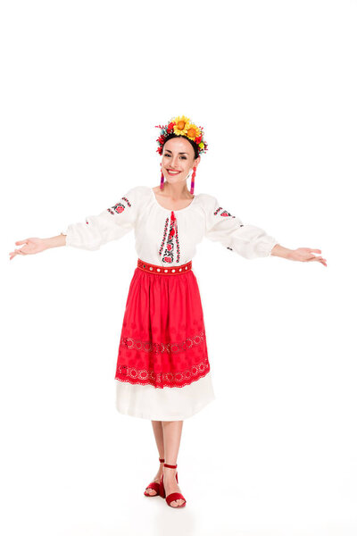 full length view of happy brunette young woman in national Ukrainian costume doing welcome gesture isolated on white
