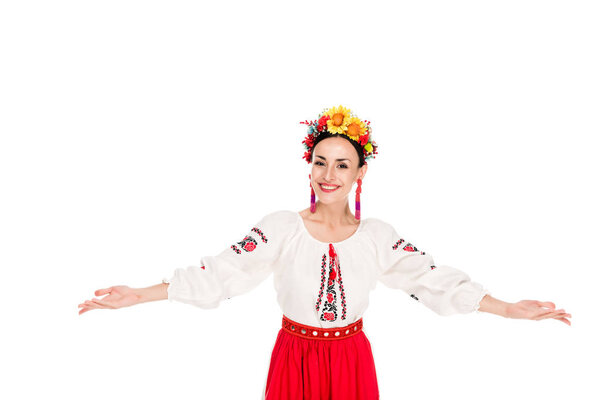 happy brunette young woman in national Ukrainian costume doing welcome gesture isolated on white