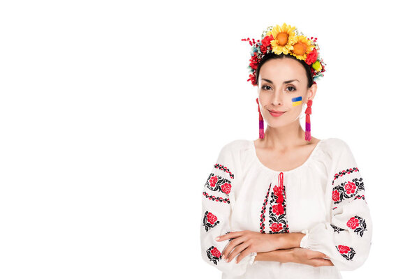 брюнетка молодая женщина в национальной украинской вышитой рубашке и цветочном венке со скрещенными руками, изолированными на белом
