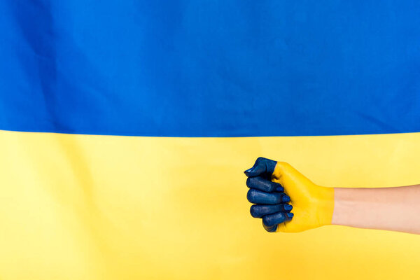 partial view of painted hand on Ukrainian flag background