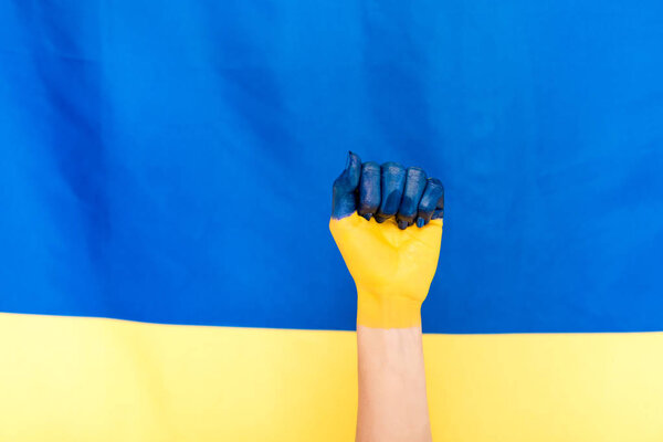 cropped view of painted hand on Ukrainian flag background