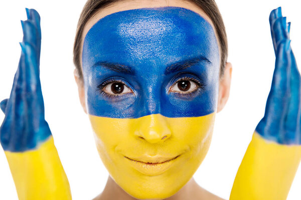 portrait of young smiling woman with painted Ukrainian flag on skin looking at camera isolated on white