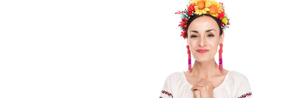 happy brunette young woman in national Ukrainian embroidered shirt and floral wreath isolated on white, panoramic shot