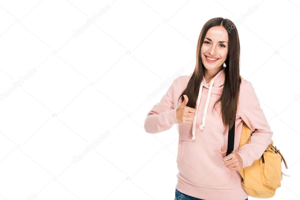 smiling brunette girl with backpack showing thumb up isolated on white