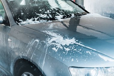 selective focus of grey auto with white foam in car wash  clipart