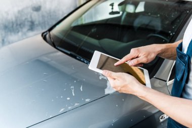 boş ekranlı dijital tablette parmakla işaret eden araç temizleyicisinin seçici odağı 
